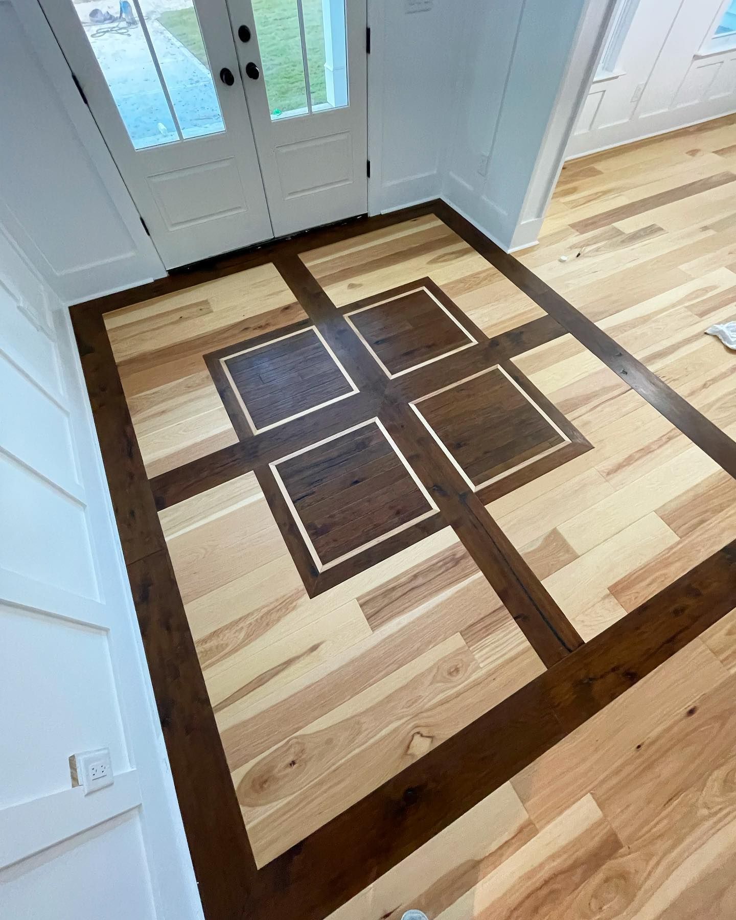 A wooden floor with squares on it in a room.