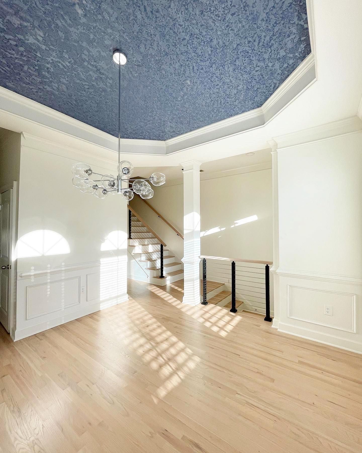 An empty room with a blue ceiling and stairs.