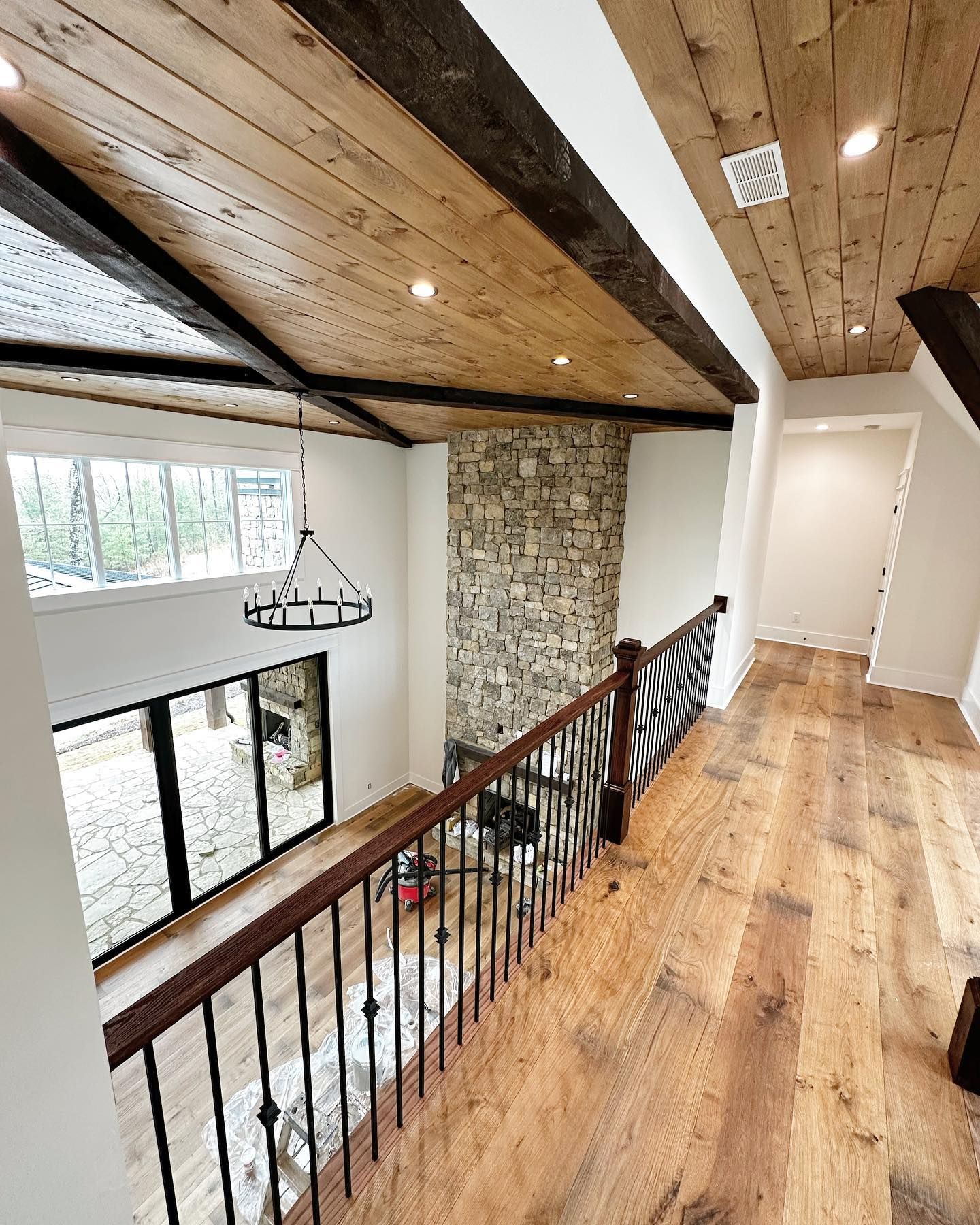 An aerial view of a hallway with hardwood floors and a wooden ceiling.
