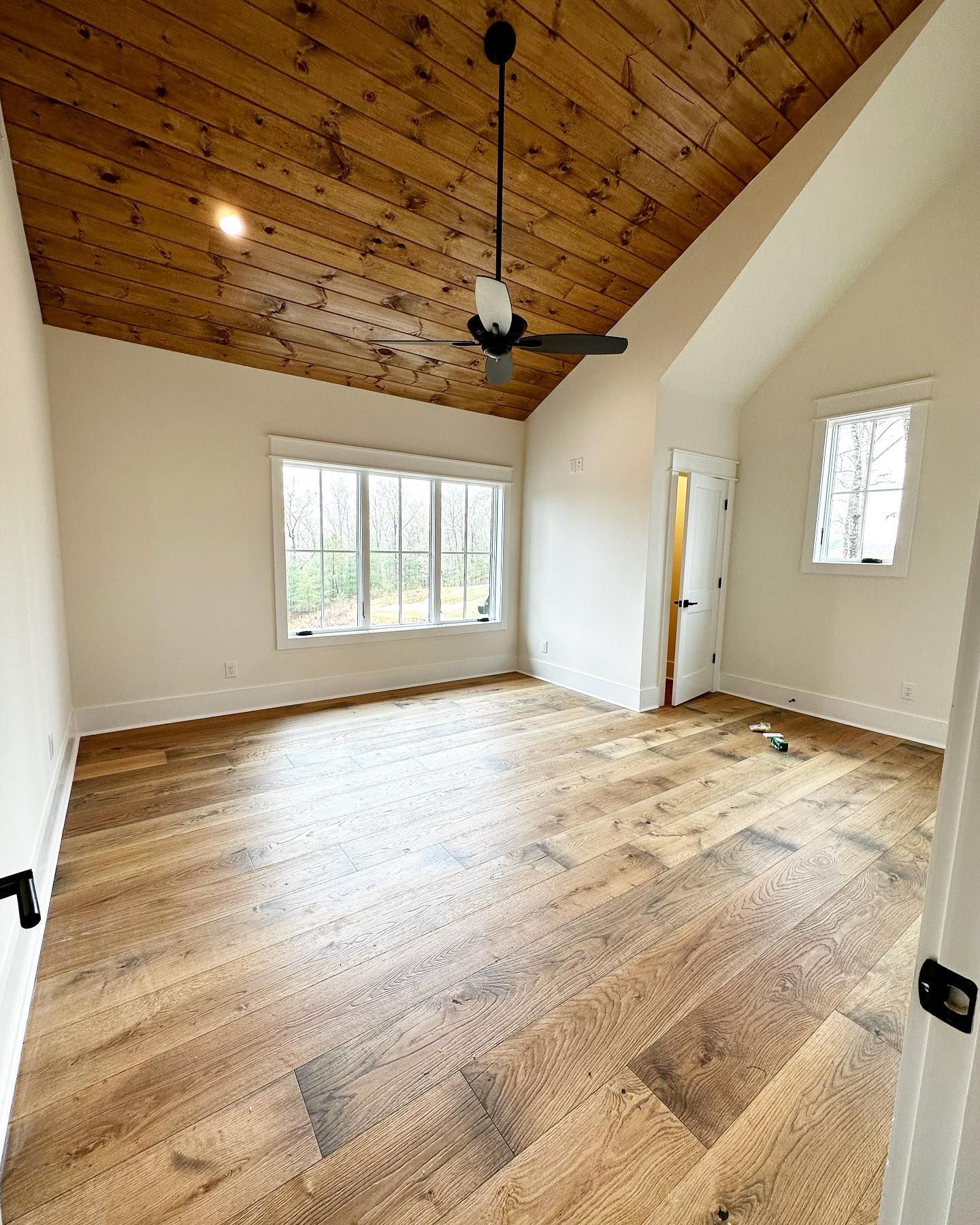 An empty room with wooden floors and a ceiling fan.