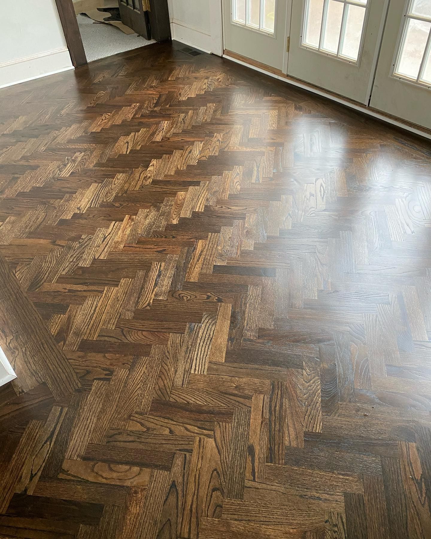 A wooden floor with a herringbone pattern in a room.