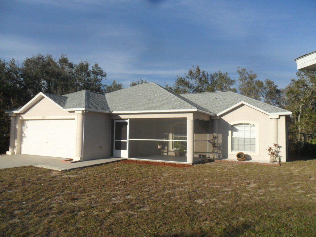 Cream colored house with a light gray roof and sun room in front of the house.