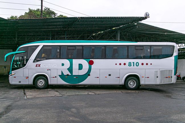Um ônibus branco verde na rodoviária com a logotipo da RD Transportes estacionado