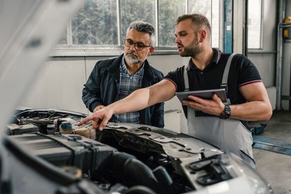 Two mechanics are working under a car in a garage.