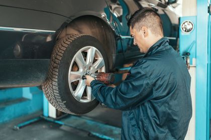 Two mechanics are working under a car in a garage.