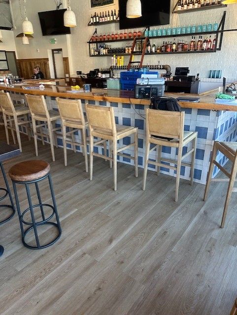 Empty bar interior with wooden stools, blue chairs, and hanging lights
