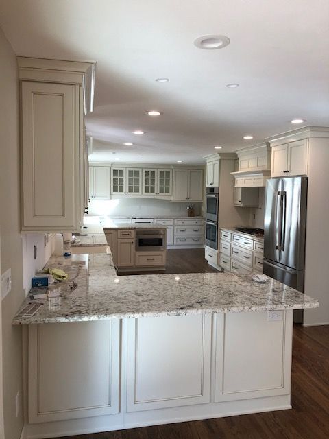 Kitchen with long wooden cabinets, granite countertop, and tiled backsplash along a hardwood floor.
