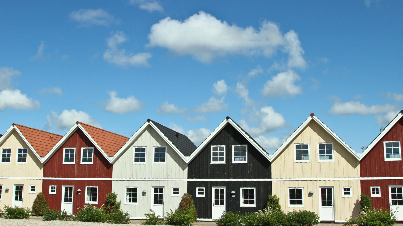 Row of colorful seaside-style houses under a blue sky with clouds