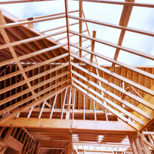 Wooden house framing with exposed roof trusses and beams under construction