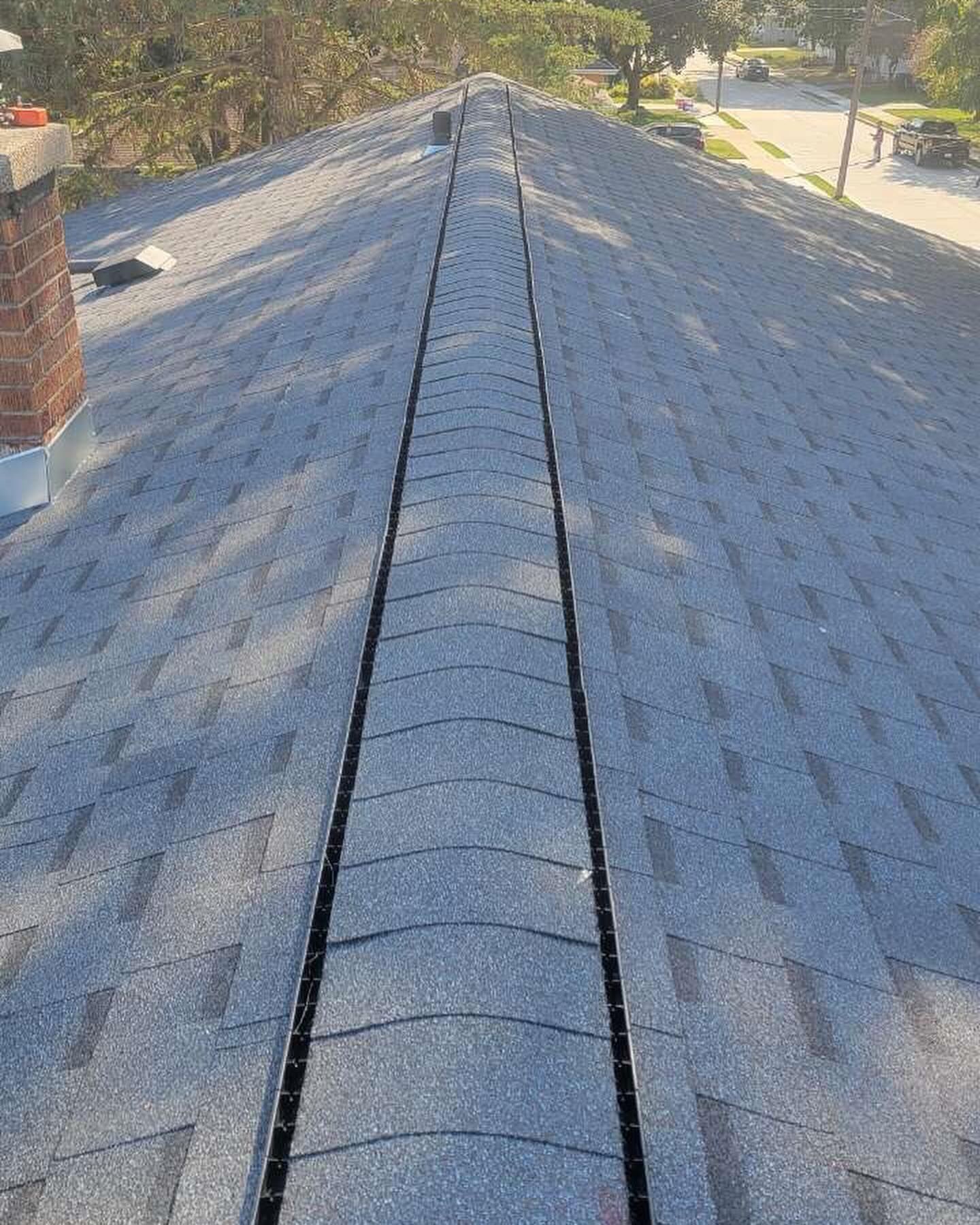 A close up of a roof with shingles and a chimney.