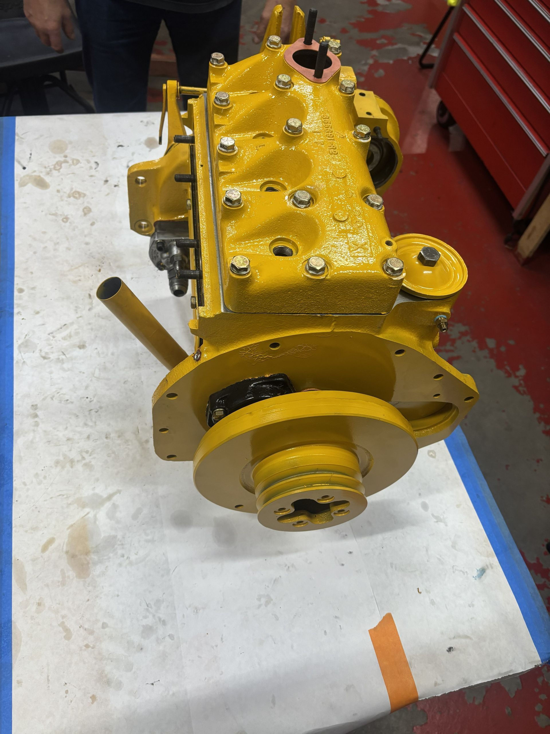 Yellow painted industrial gearbox on a white surface.