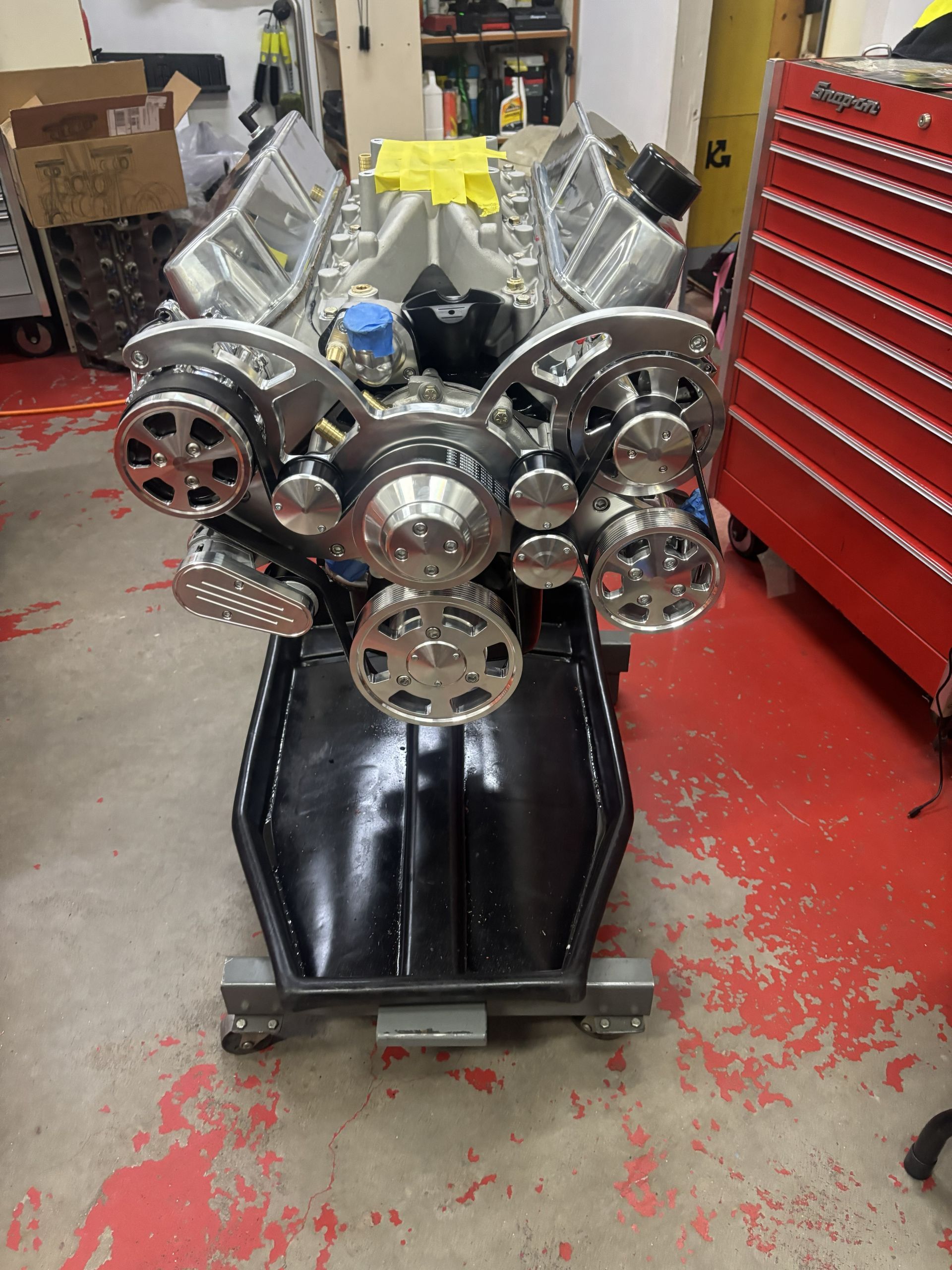 Shiny engine on a black stand in a workshop, with silver, chrome, and blue components.