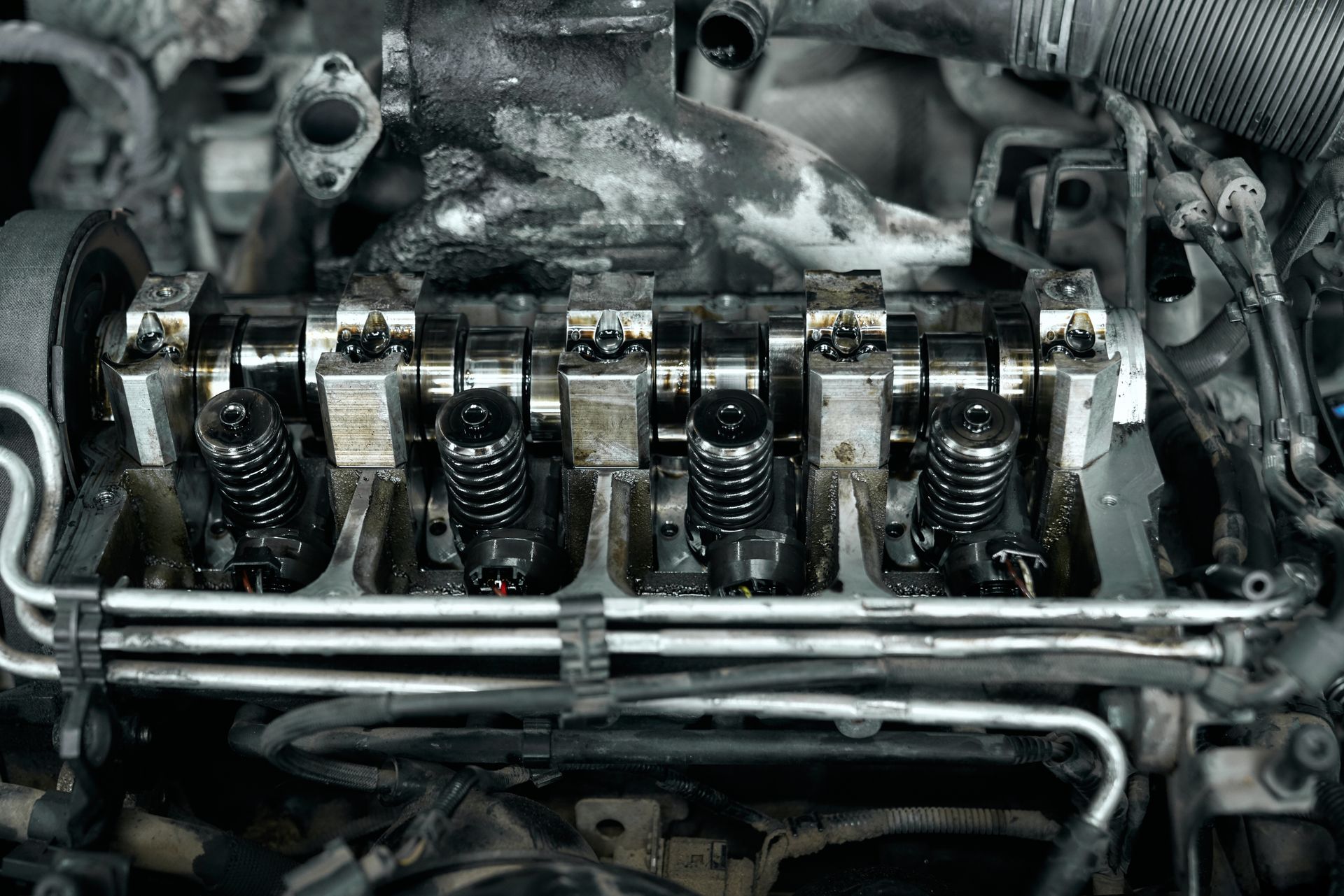Engine cylinder head, showing valves, springs, and rocker arms, covered in grime.