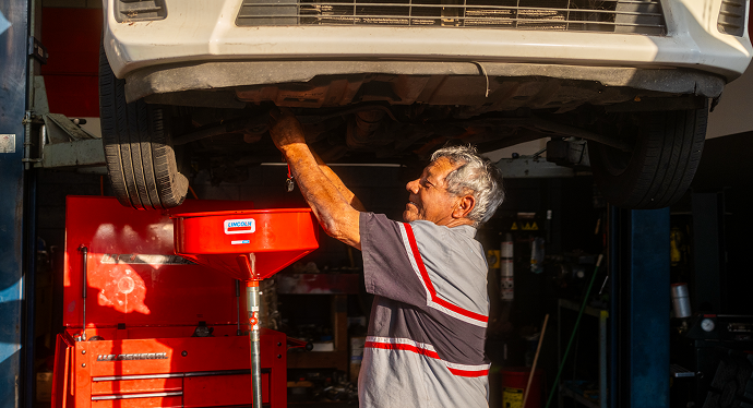 Mechanic working on a car's brake rotor, hands covered in grease.