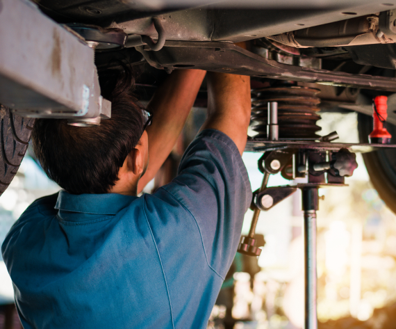 A white car with the hood open is on a lift in a garage. | Import Specialty Service