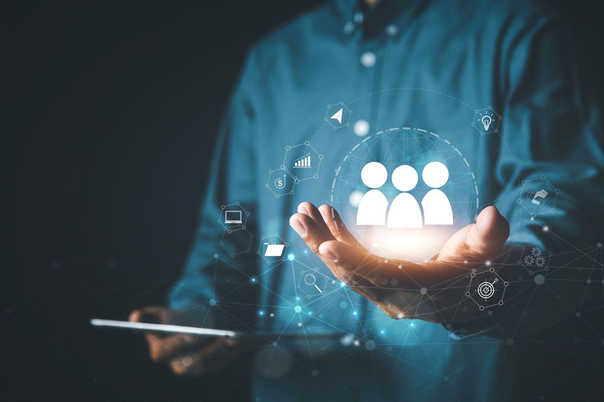 A man is holding a tablet and a group of people icon in his hands.