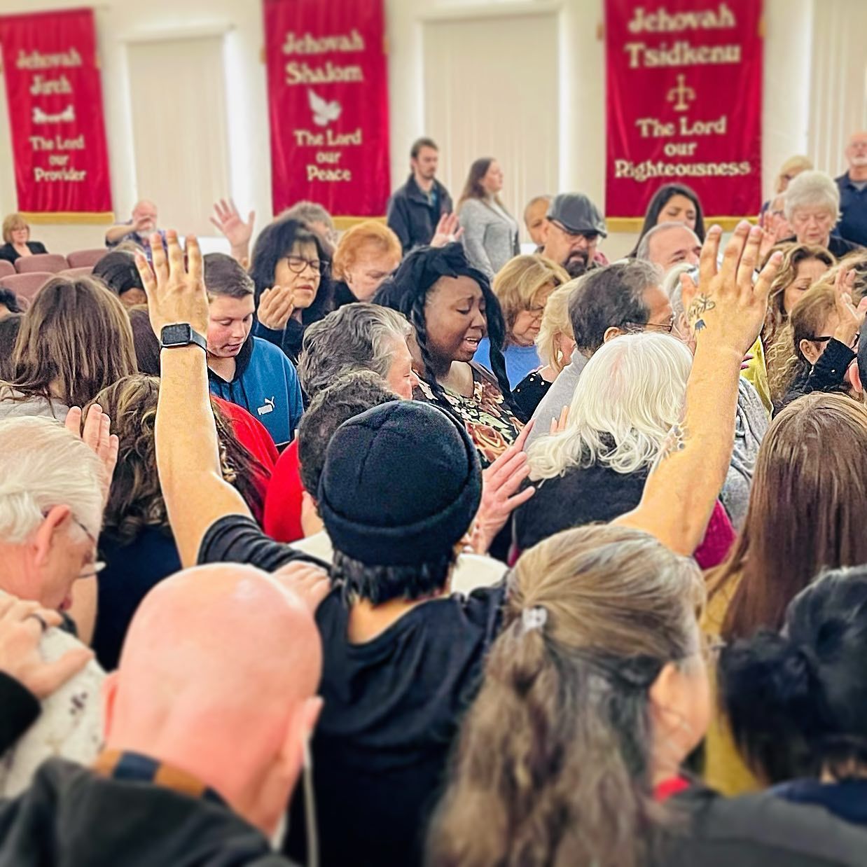 a large group of people are raising their hands in the air