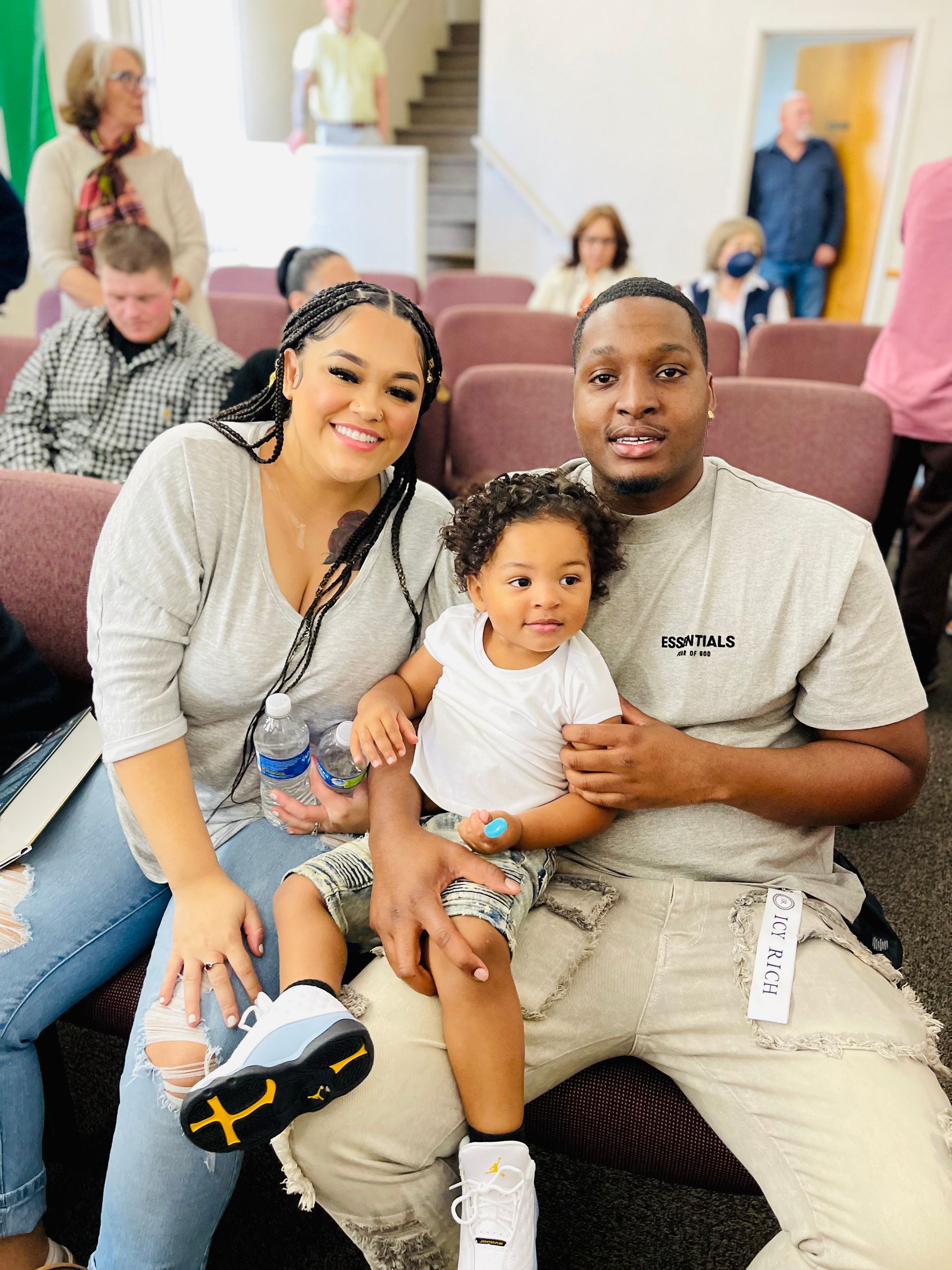 A man and woman are sitting in a chair with a baby.