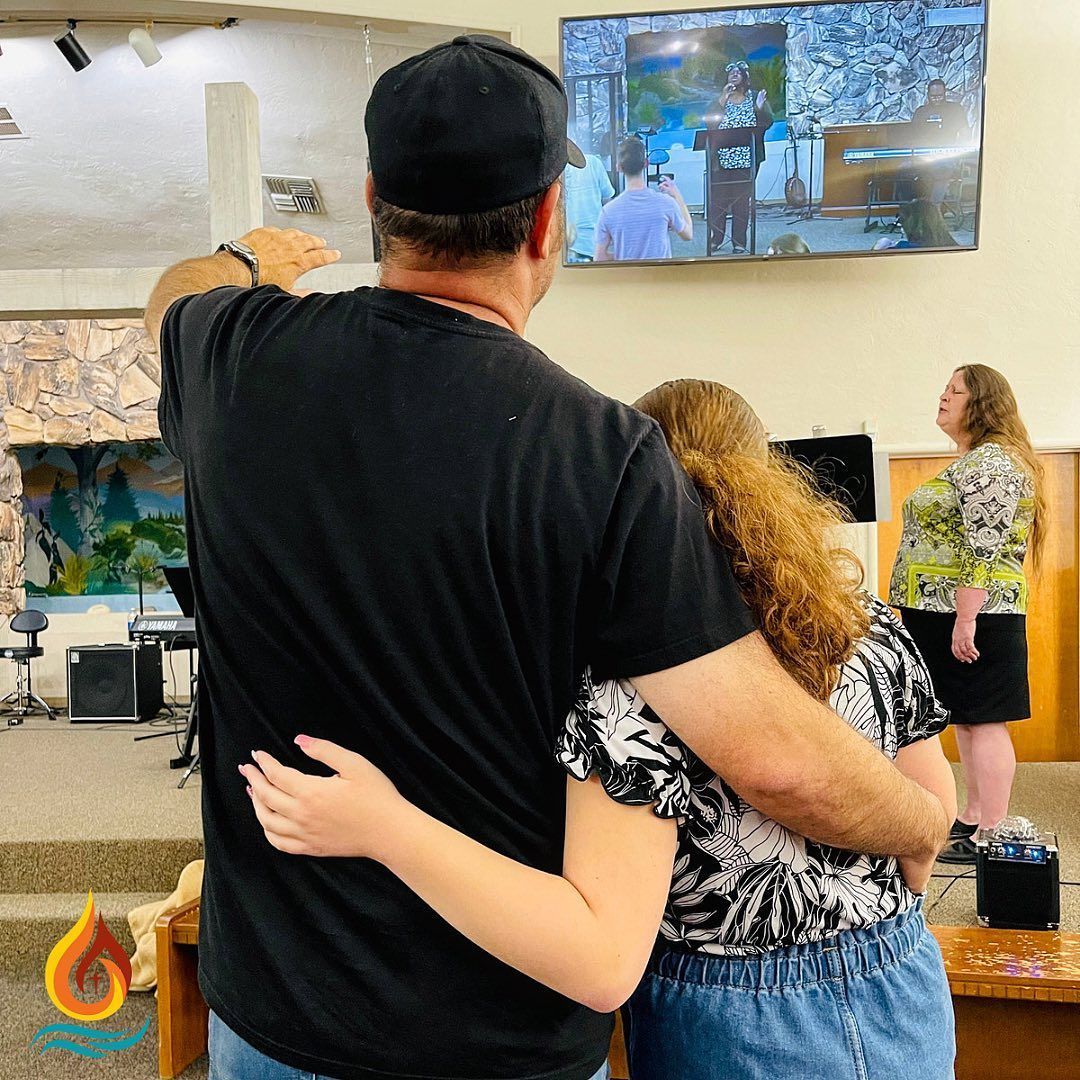 a man and a woman are hugging while watching a television .