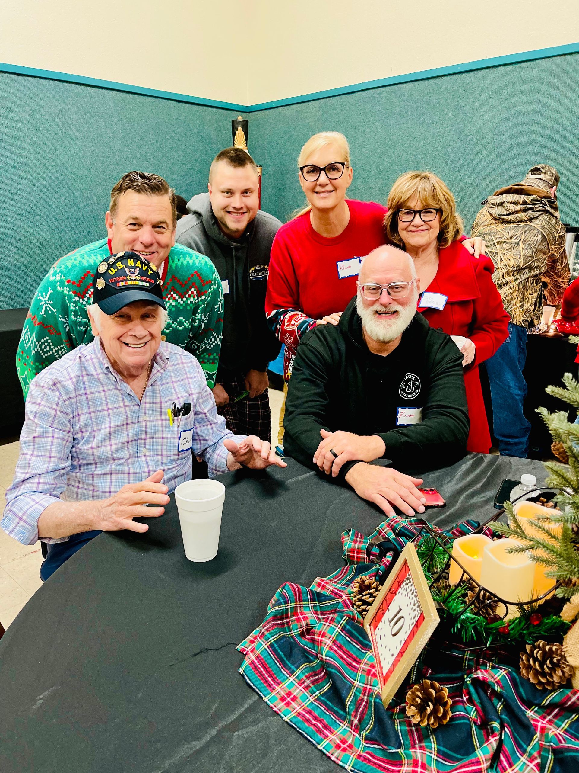 A group of people are posing for a picture while sitting at a table.
