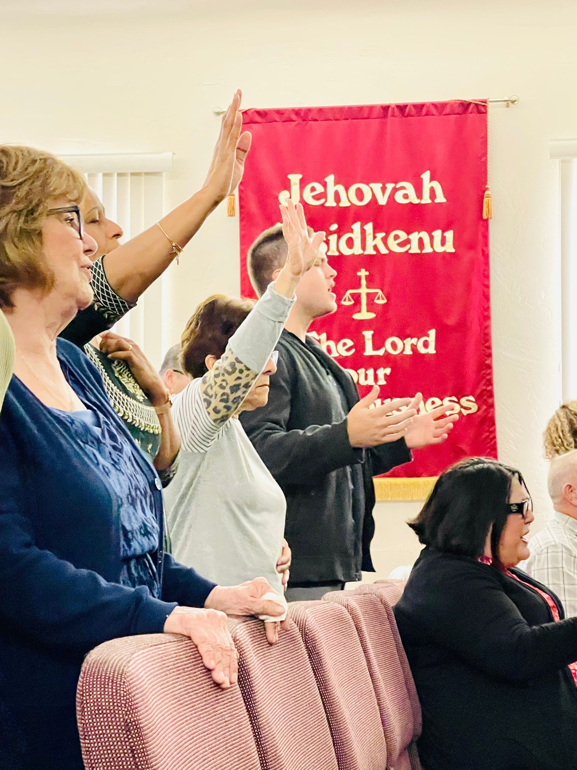 A group of people are standing in front of a banner that says jehovah idkenu