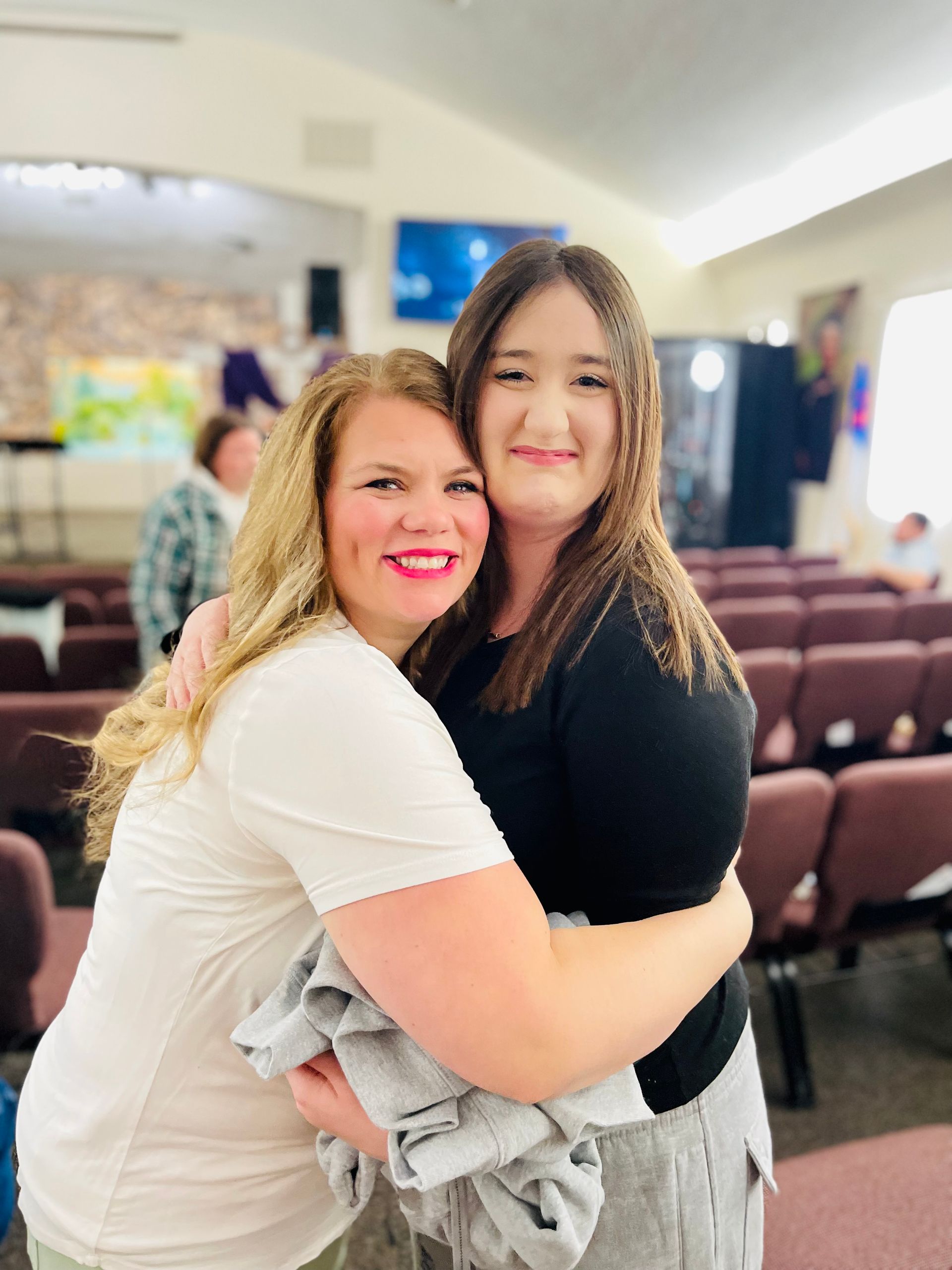 Two women are hugging each other in a church