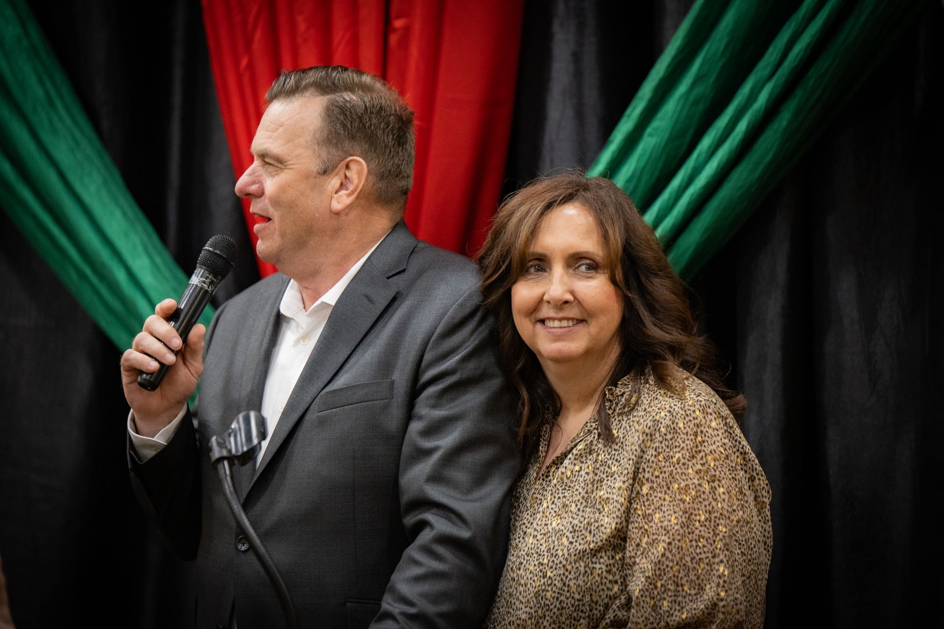 A man is holding a microphone while standing next to a woman.
