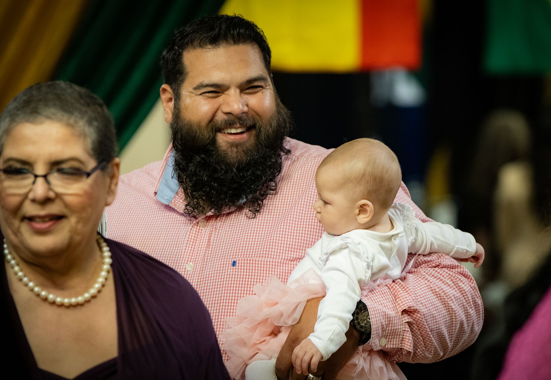 A man with a beard is holding a baby in his arms.