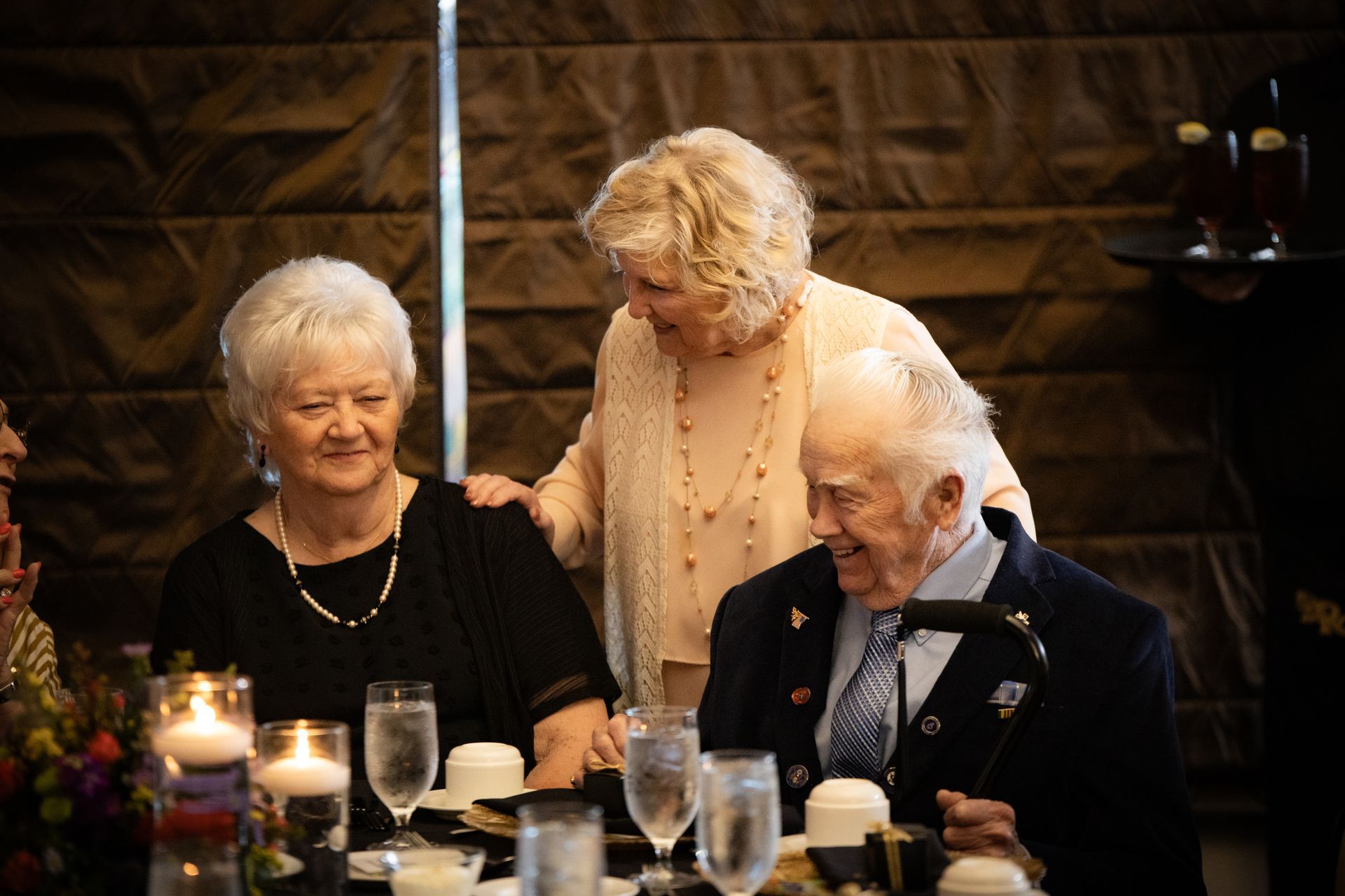 A man and two women are sitting at a table with glasses of water.