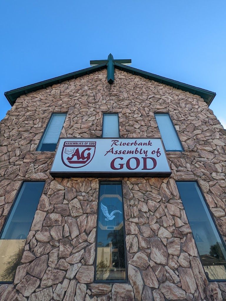 a stone building with a sign that says riverbank assembly of god on it .