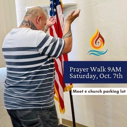a man in a striped shirt is praying in front of an american flag .
