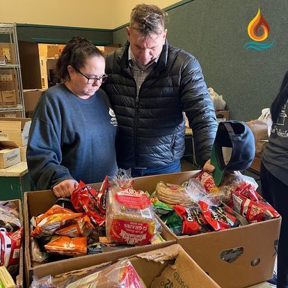 a man and a woman are looking at a box of food .