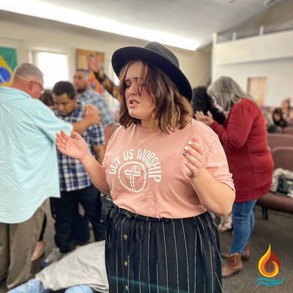 a woman in a hat is standing in front of a group of people in a church .
