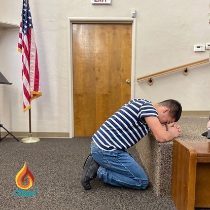 a man is kneeling down in front of an american flag in a room .