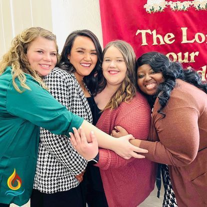 a group of women are standing next to each other and putting their hands together .