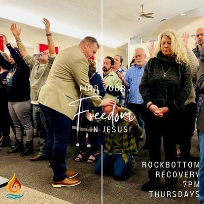 a group of people are standing in a room with their hands in the air .