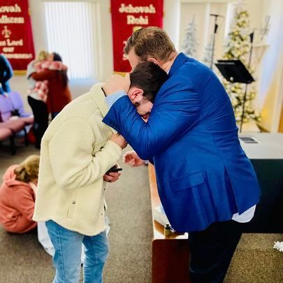 a man in a blue suit is hugging another man