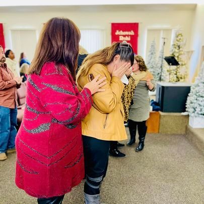 two women are standing next to each other in a room covering their faces .