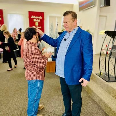 a man in a blue jacket is talking to another man in a church .