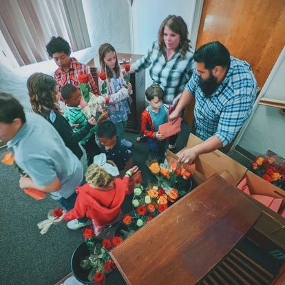 a group of people are standing around a table with flowers .
