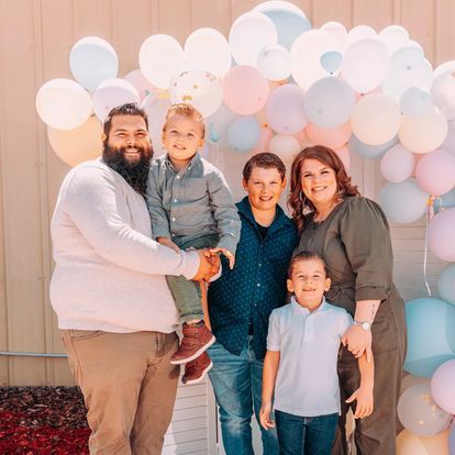 a family is posing for a picture in front of balloons .