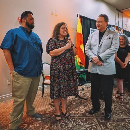 a group of people are standing in a room with a woman holding a microphone .