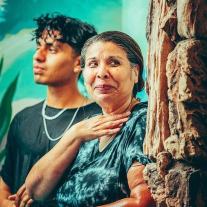 a man and a woman are standing next to each other in front of a stone wall .
