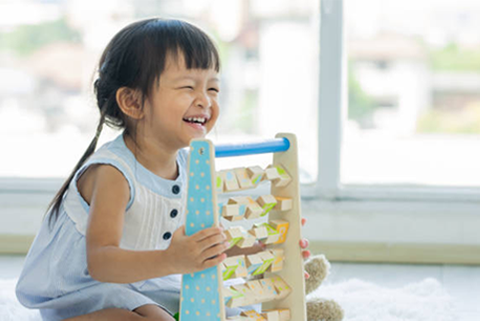 A little girl is sitting on the floor playing with a wooden toy.