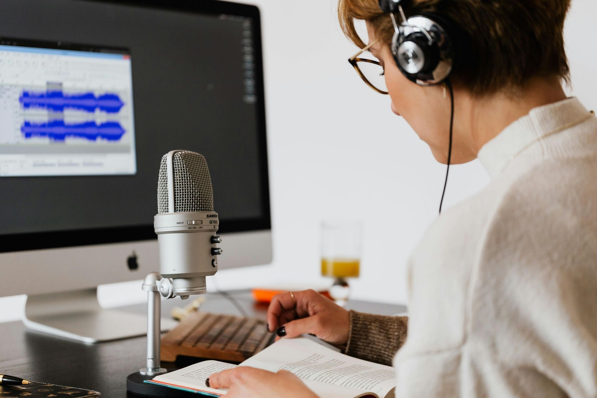 A woman wearing headphones is sitting in front of a microphone.