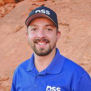 A smiling person with a beard wearing a blue polo shirt and a