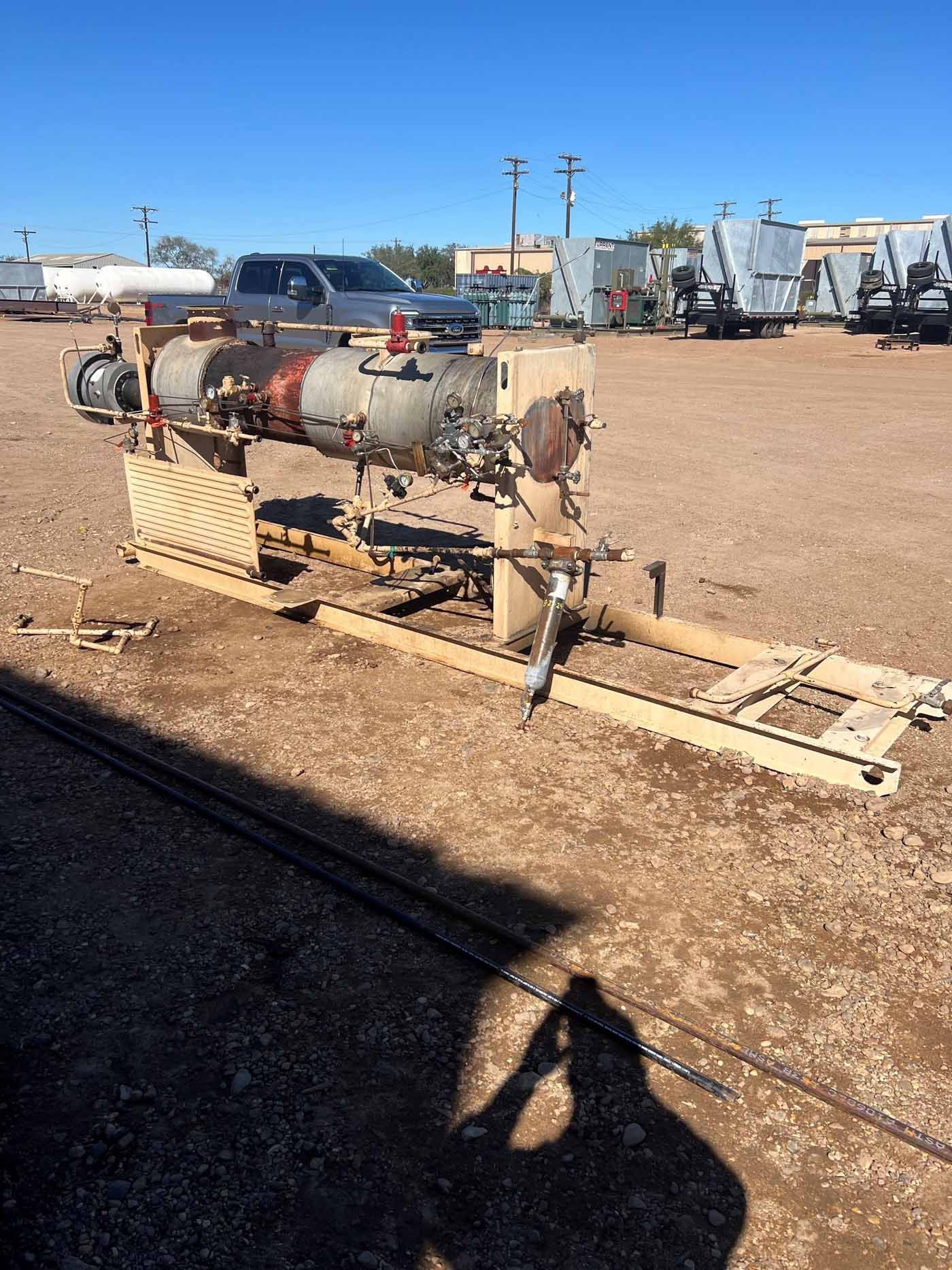 A large metal pipe is sitting in the middle of a dirt field.