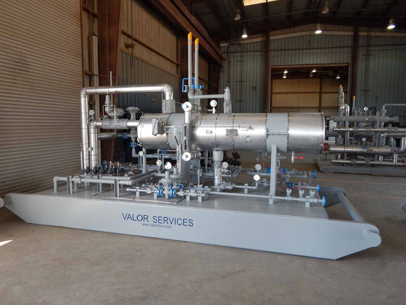 A large machine is sitting in a warehouse with pipes and valves.