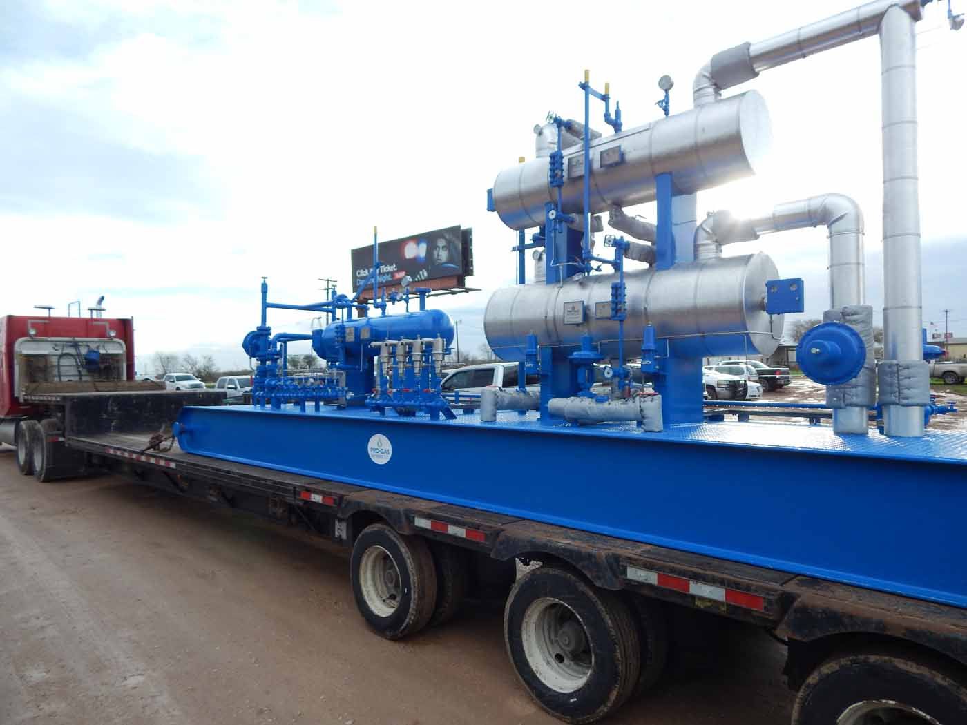A blue semi truck is carrying a large piece of equipment.
