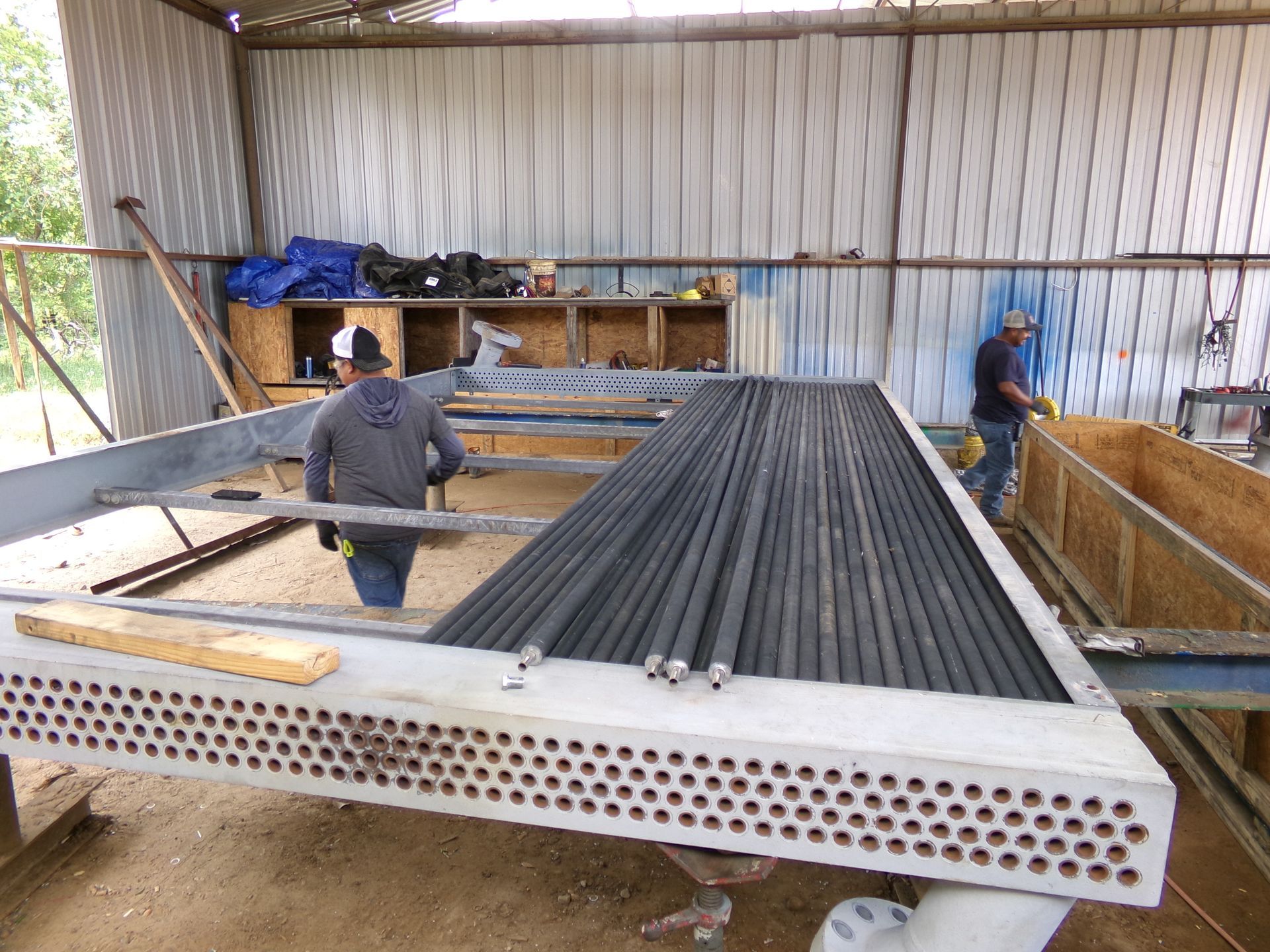 Two men are working on a large metal structure in a building